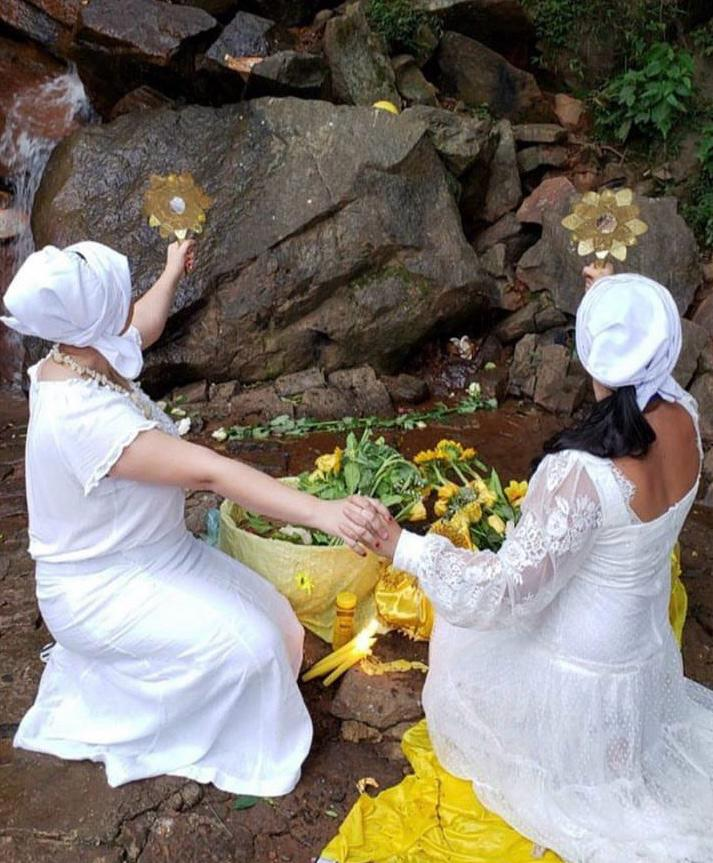 Ritual de conexão espiritual próximo à água corrente e flores amarelas