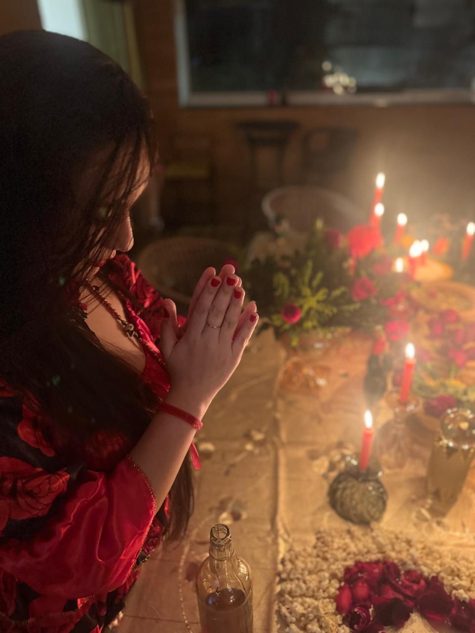 Momento de oração silenciosa em mesa espiritual com velas e rosas