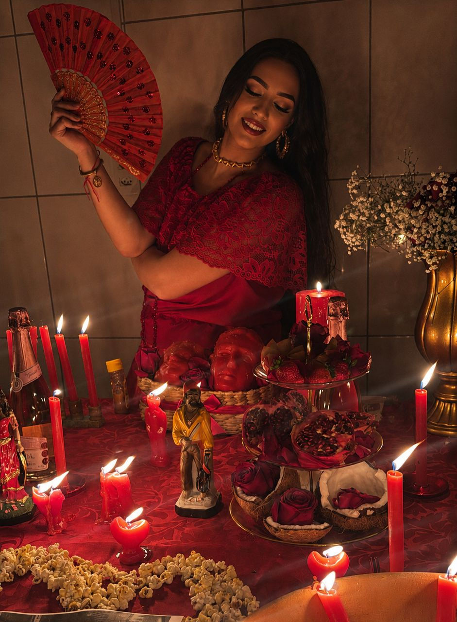 Cenário ritualístico com velas vermelhas e flores representando trabalho espiritual amoroso